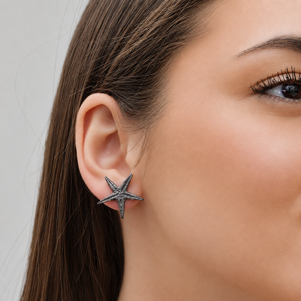 Oxidized sterling silver starfish stud earrings worn on an ear Oxidized sterling silver starfish stud earrings worn on an ear
