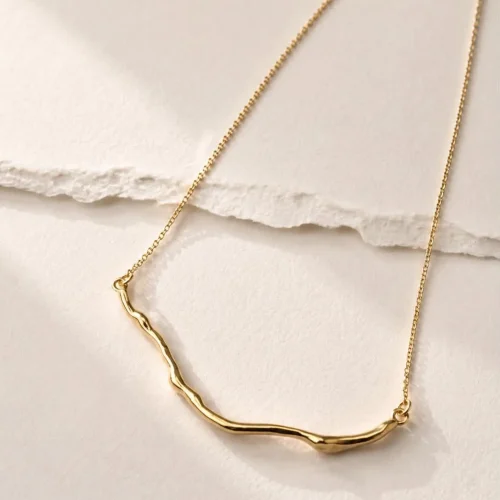 Gold organic bar necklace with a sculptural wavy pendant on a delicate chain